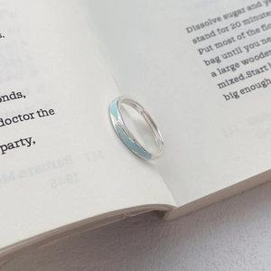 Eleganter S999 Silberring mit hellblauem Emaille-Wellenmuster auf einem weißen Buch