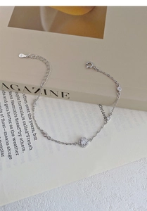 Macro shot of S999 sterling silver bracelet with zircon charms on a magazine background