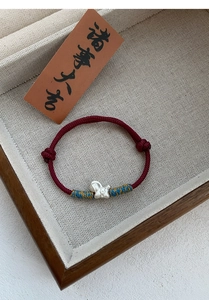 Close-up of S999 silver fish pendant on handcrafted red braided cord bracelet