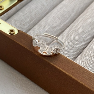 S999 silver rocking horse ring with wealth symbols on a wooden jewelry display