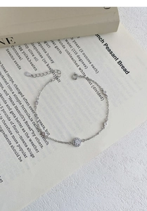 Detail of S925 silver bracelet with sparkling zircon charms on a vintage book page