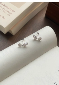 Macro shot of S999 sterling silver koi fish earrings with screw back on book pages