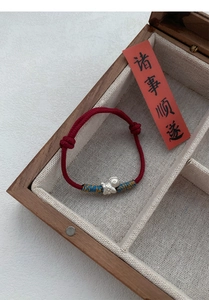 Close-up of S999 sterling silver horse charm on a hand-woven red string bracelet