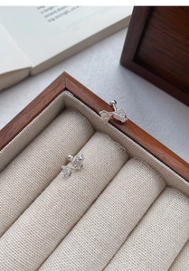 Macro detail of silver koi fish screw-back earrings on linen jewelry box lining