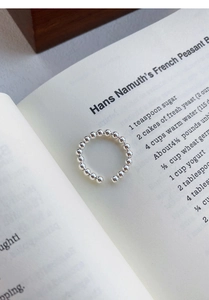 Vue macro d'une bague ouverte perlée en argent S925 sur une page de livre vintage