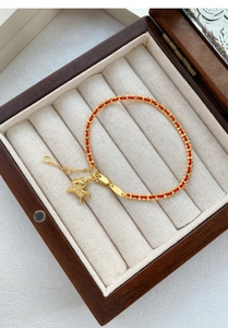 Détail du charm cheval en argent S925 sur bracelet tressé rouge dans un coffret