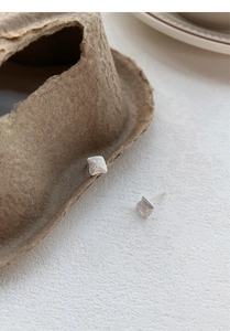 Macro detail of square matte S999 silver studs with a minimalist brushed texture finish