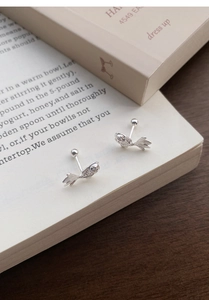 Detailed view of silver koi fish stud earrings with secure screw ball back on vintage book