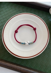 Detailed shot of S999 silver zodiac horse charm on hand-woven red cord bracelet