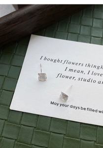 Macro shot of S999 silver square stud earrings with brushed texture on a white card