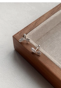 Detailed close-up of S925 sterling silver koi fish earrings on a beige linen display