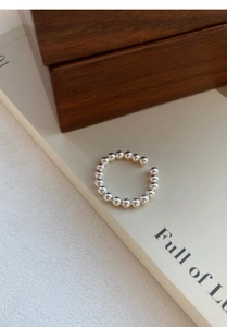 Gros plan d'une bague ouverte minimaliste en argent S925 avec billes polies brillantes