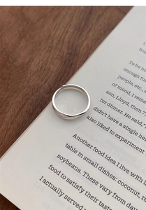 Minimalistischer S999 Sterlingsilber Ring mit Wellendesign auf einem offenen Buch