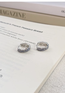 Macro detail of irregular S925 silver hoop earrings with light purple enamel texture