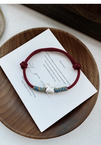 Detailed macro shot of red braided S999 silver bracelet with matte butterfly charm
