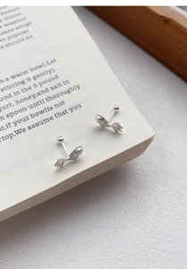 Macro shot of silver koi fish screw back earrings on vintage book pages detail