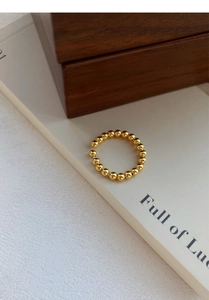 Gros plan d'une bague ouverte minimaliste avec billes en or 18 carats et design ajustable