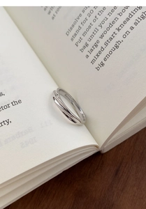 Detailaufnahme eines minimalistischen S999 Silberrings mit gedrehtem Design in einem Buch