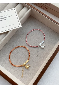 Détail de bracelets en argent S925 avec corde rouge et breloques cheval dorées et argent