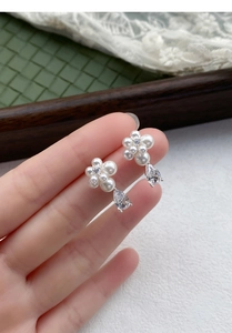 Close-up of S999 silver flower earrings with small pearls and a large pear-cut zircon drop