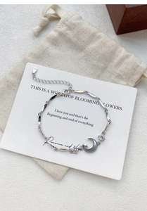 Macro detail of S925 sterling silver moon and star bracelet with a beige jewelry pouch