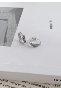 Detail of irregular S925 sterling silver hoop earrings with blue enamel and lava texture