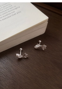 Macro detail of S999 sterling silver koi fish screw back earrings on wooden surface