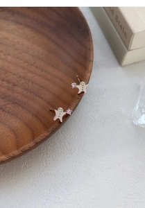Nahaufnahme der S999 Silber Lebkuchenmann Ohrstecker mit rosa Zirkon und lächelndem Gesicht