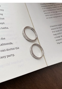 Close-up of S999 sterling silver open rings with butterfly and floral engravings on a book