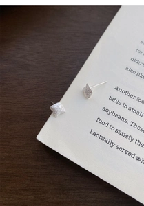 Macro detail of silver minimalist square studs with brushed starlight texture