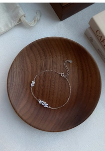 Detailed macro view of S925 sterling silver floral bracelet with moonstone pendant in wooden bowl