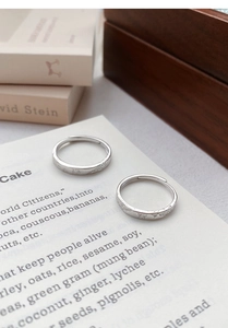 Detail of adjustable silver rings with butterfly and floral engravings on vintage book