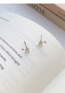 Nahaufnahme der S999 Lebkuchenmann-Ohrstecker aus Silber mit rosa Zirkon auf Buch