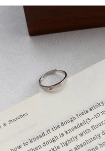 Close-up of S999 sterling silver ring featuring embossed butterfly and floral patterns