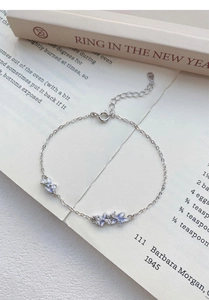 Detailed shot of S925 silver bracelet with light blue flowers on vintage book background
