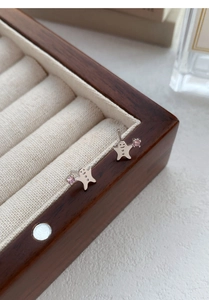 Makroaufnahme von Lebkuchenmann-Ohrringen aus Silber mit rosa Edelstein auf Samtdisplay