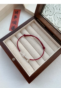 Close-up of S925 silver star charm and bell on a hand-woven red string bracelet