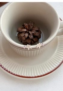 Süße S999 Lebkuchenmann-Ohrringe aus Silber mit rosa Zirkon an einer Kaffeetasse