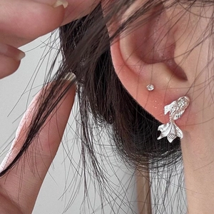 Macro shot of S999 sterling silver koi fish earrings with zircon studs on a model