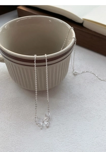 Detail of silver S999 butterfly necklace with zircon crystals hanging on ceramic cup