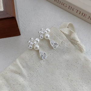 Elegant S999 silver pearl flower earrings with pear-cut zircon on beige linen pouch