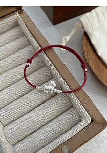 Close-up of S999 silver horse charm on red braided rope bracelet with coin pattern