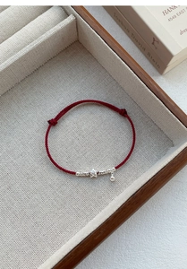 Detail of red braided S925 silver star bracelet with bell in a gift box setup