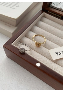 Macro detail of gold and silver flower rings with zircon inlay in a wooden jewelry box
