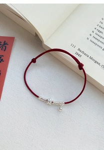 Detail view of red braided S925 silver bracelet with star charm and small bell