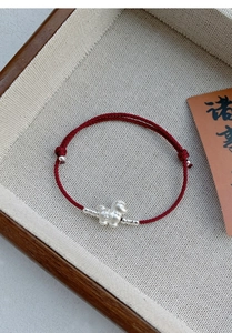 Macro shot of S999 silver sheep charm on adjustable red rope bracelet with coin details