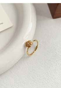 Macro detail of golden flower ring with brushed texture petals and center zircon stone