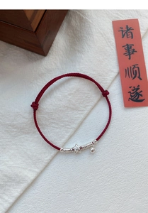 Macro detail of red woven rope bracelet with S925 silver star charm and lucky bell charm