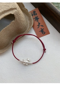 Close-up of S999 silver horse charm on a hand-woven red rope bracelet with luck charm