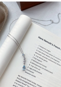 Detailed view of S999 silver blue teardrop zircon necklace on an open vintage book